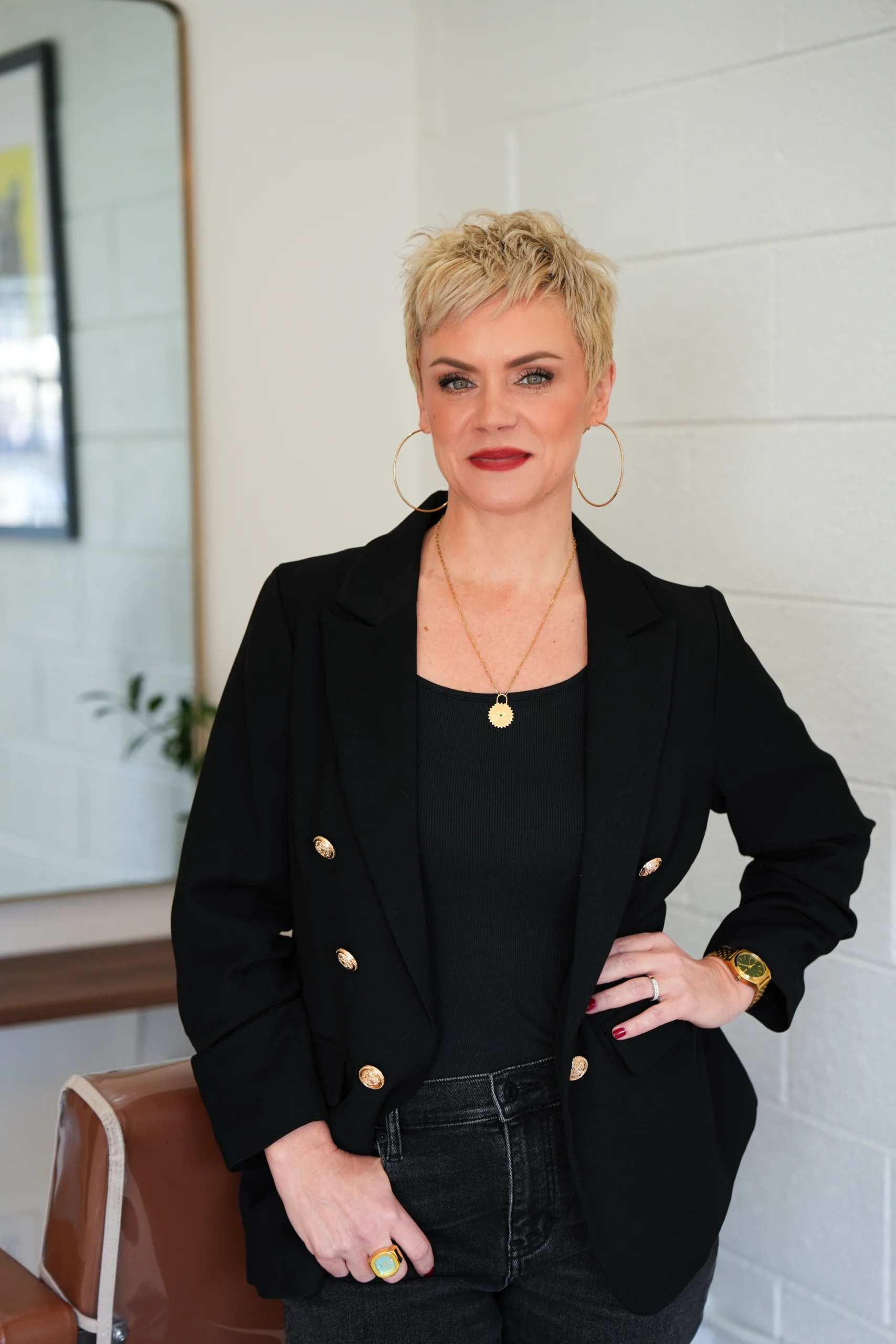 Owner and lead artist of a beauty and hair salon in Denver posing in a modern studio, showcasing professional style and confidence.